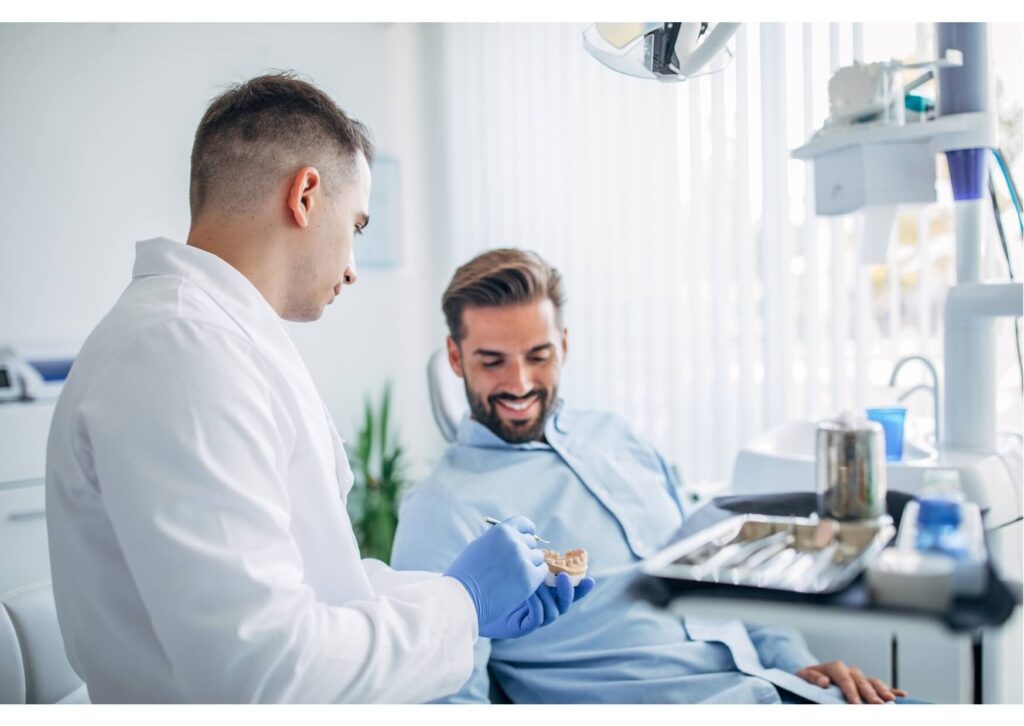 Dental professional showing a tooth implant model to explain the pros and cons of dental implants during treatment planning