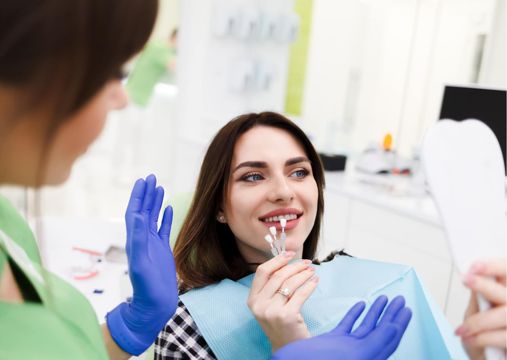 Patient comparing tooth shade samples during a cosmetic consultation, discussing porcelain veneers longevity and long-term smile aesthetics.