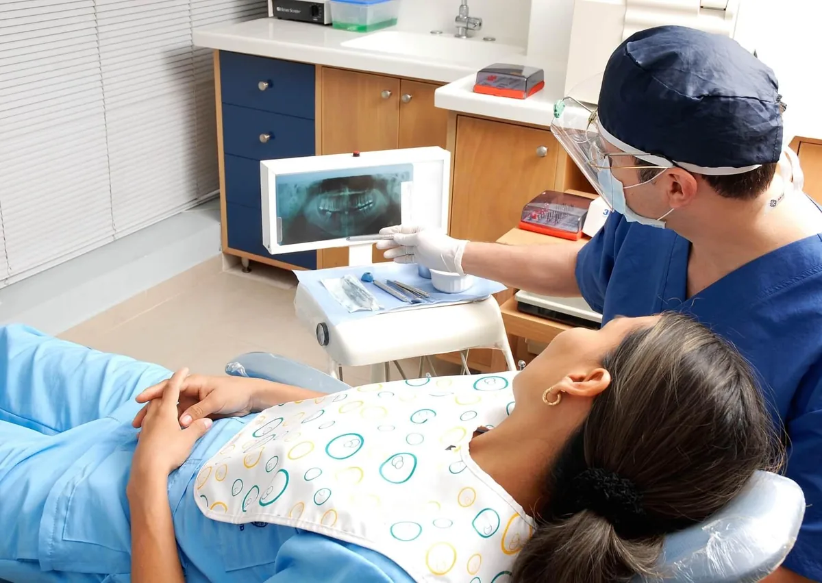 Dentist reviewing a dental X-ray with a patient during an evaluation for single tooth implant cost and treatment planning.