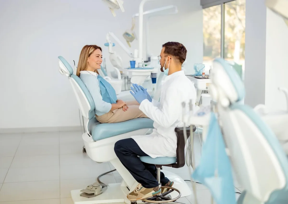 Dentist discussing what to eat after dental implant surgery with a patient during a follow-up visit.