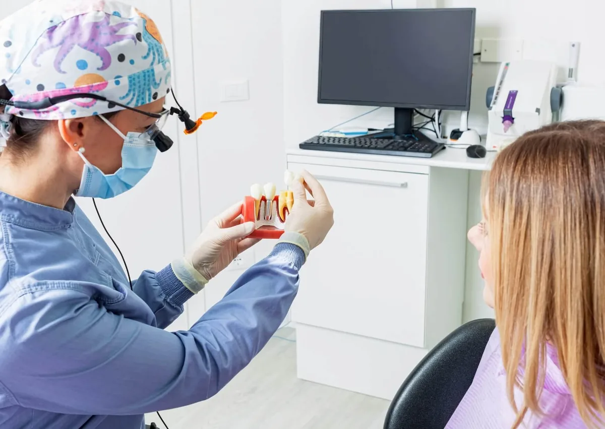 Dentist explaining dental implant removal using a model of a dental implant and surrounding teeth.