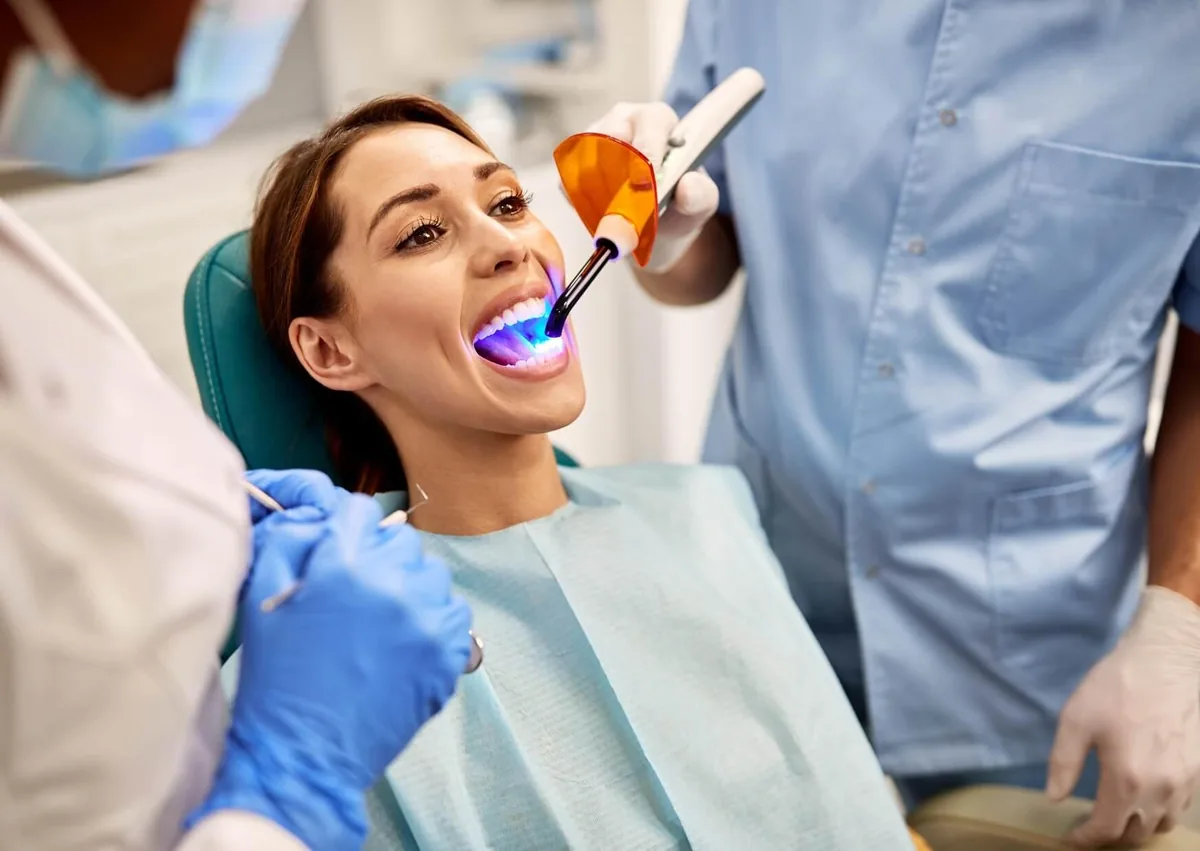 Dentist applying and curing tooth-colored resin during a dental bonding procedure.