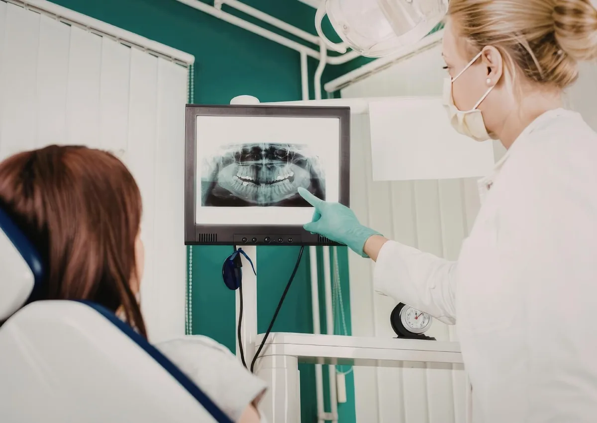 Dentist reviewing a dental X-ray with a patient while discussing dental bridges and implants.
