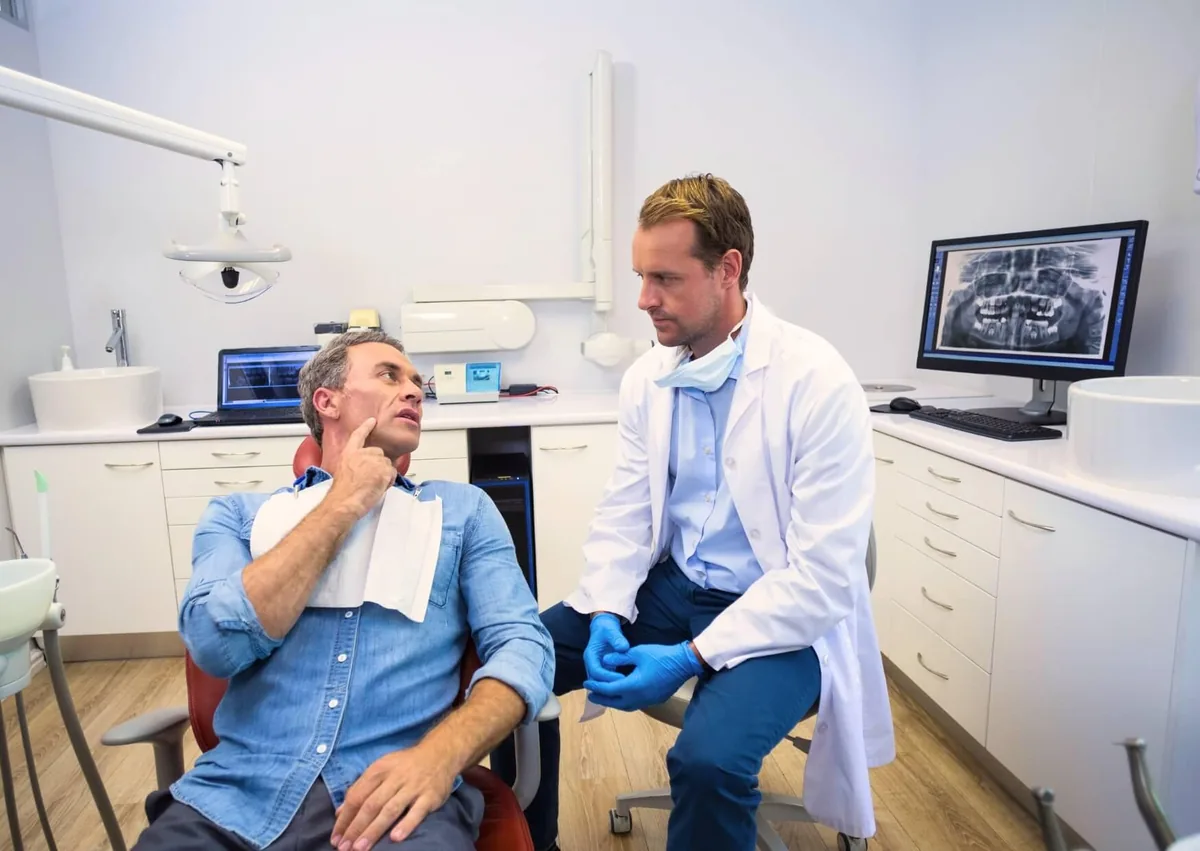 Dentist discussing whether it is too late to get dental implants with a patient after reviewing dental X-rays.