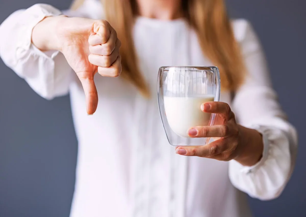 Woman holding a glass of milk while avoiding dairy after dental implant surgery.